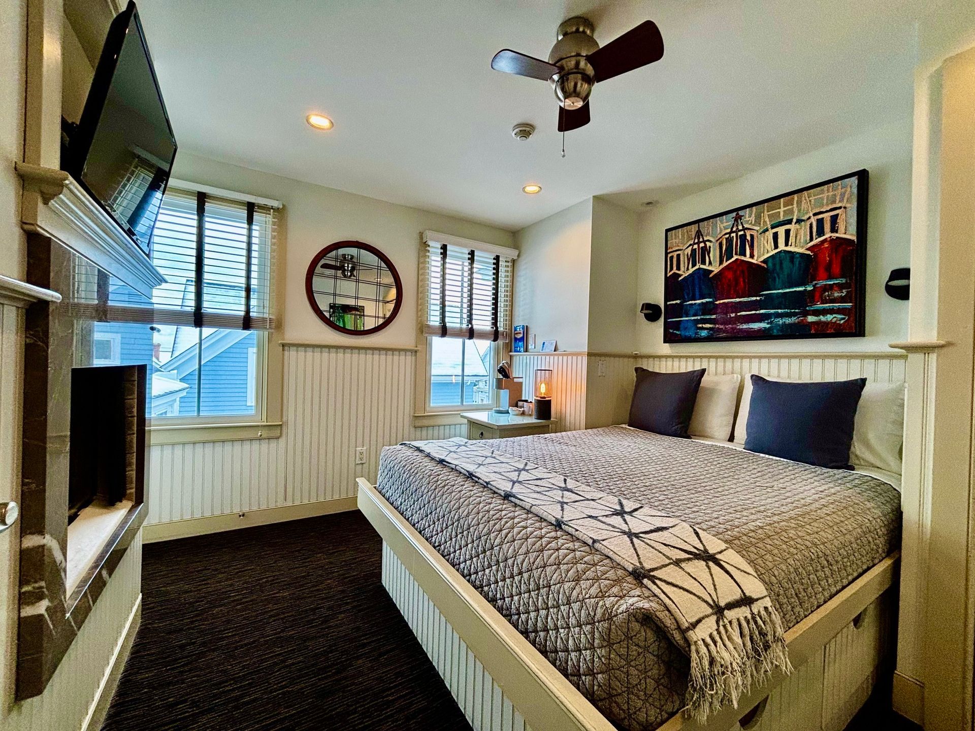 A bedroom with a bed , television , fireplace and ceiling fan.