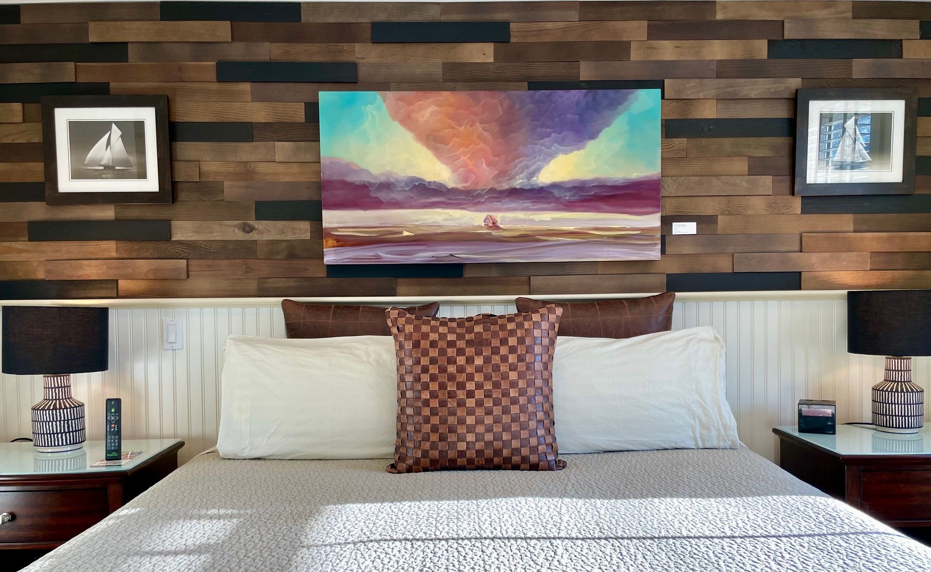 A bedroom with a large painting on the wall above the bed