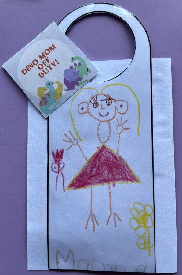 Child's drawing on a door hanger. A stick figure with a red dress waves.