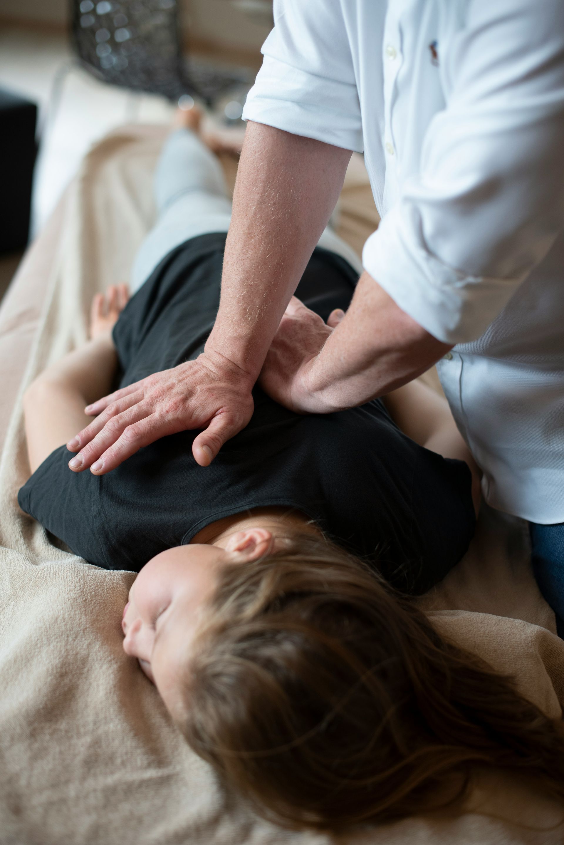 Person receiving a massage on a couch, with hands pressing on their back and shoulder