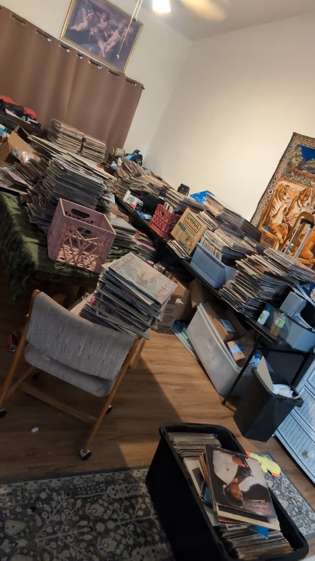 Tables covered in stacks of LPs while a large collection is sorted