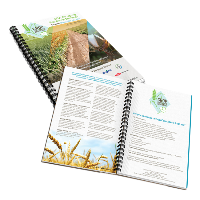Open spiral-bound agricultural brochure with crop and field photos on white background