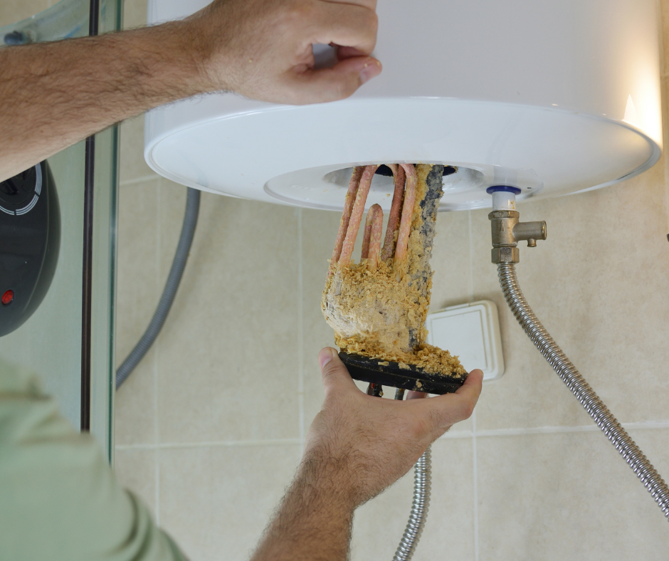 Person cleaning a dusty water heater, removing a corroded heating element in a tiled bathroom
