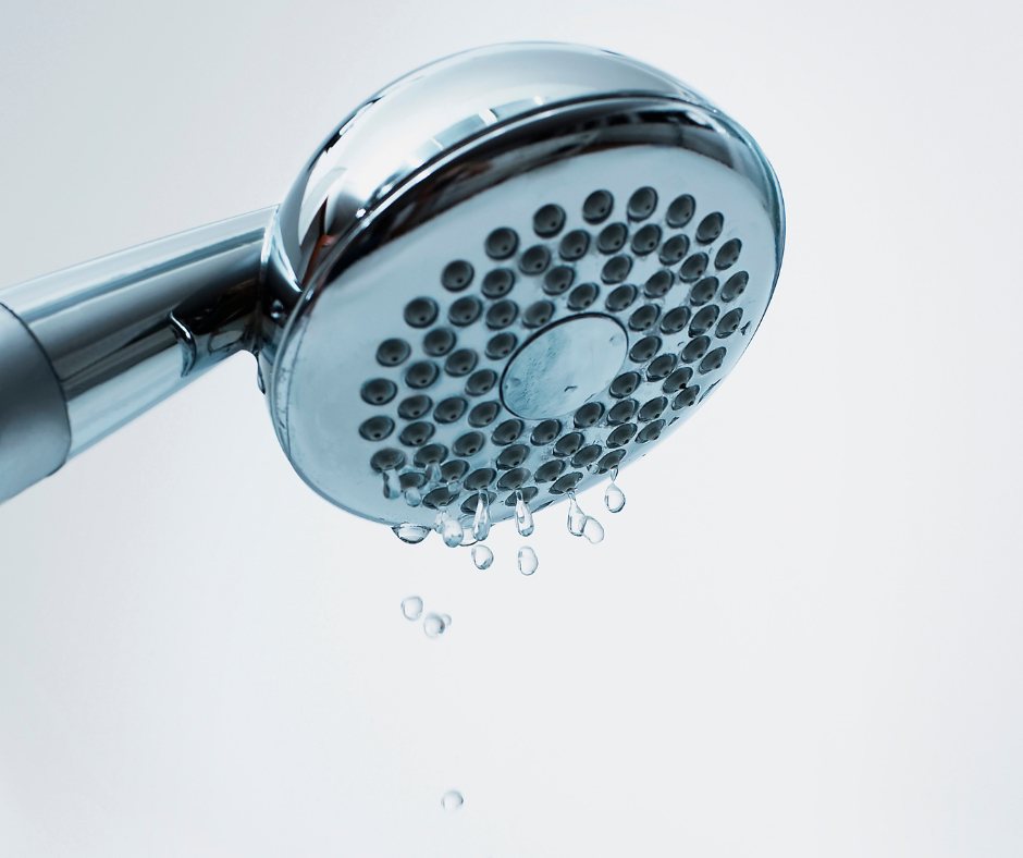 Chrome showerhead dripping water against a light background