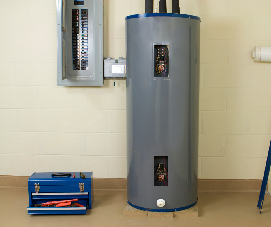 Gray water heater in a utility room, with electrical panels and a blue toolbox nearby.
