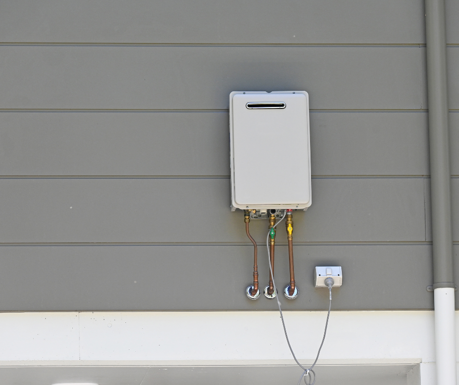Wall-mounted white utility box with exposed pipes and wiring on a gray house exterior.