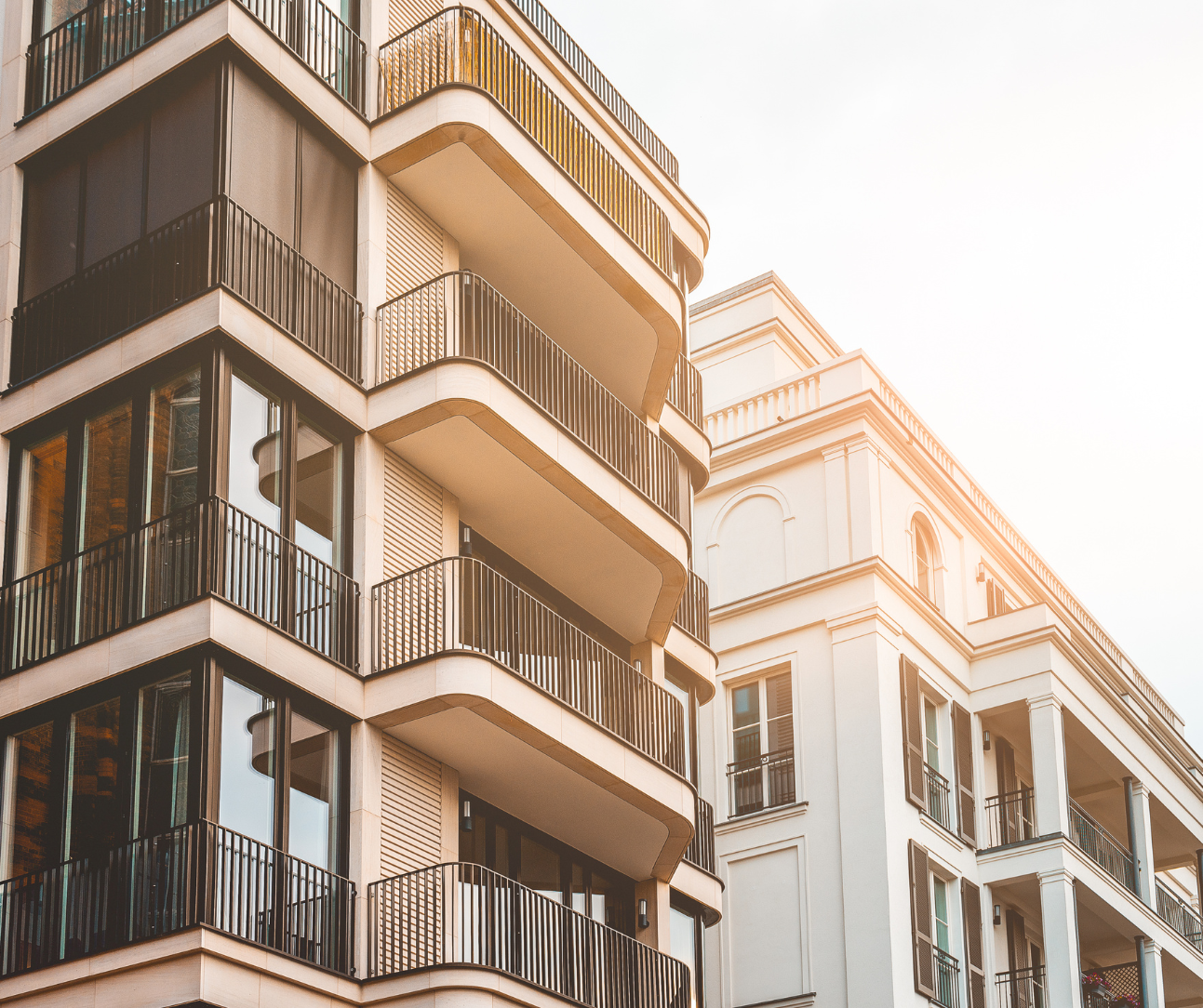 Sunlit balconies on modern apartment buildings with warm beige and white facades