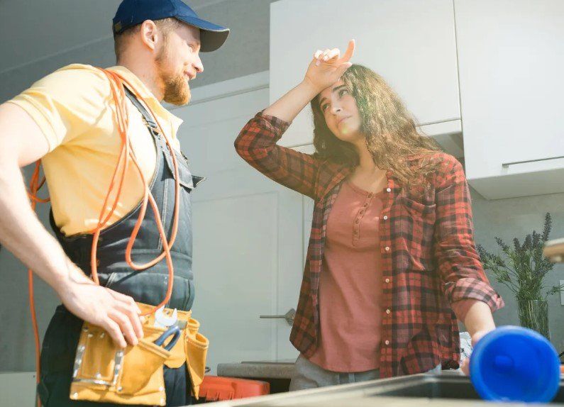 Worker in orange safety gear talking with a woman in a plaid shirt indoors