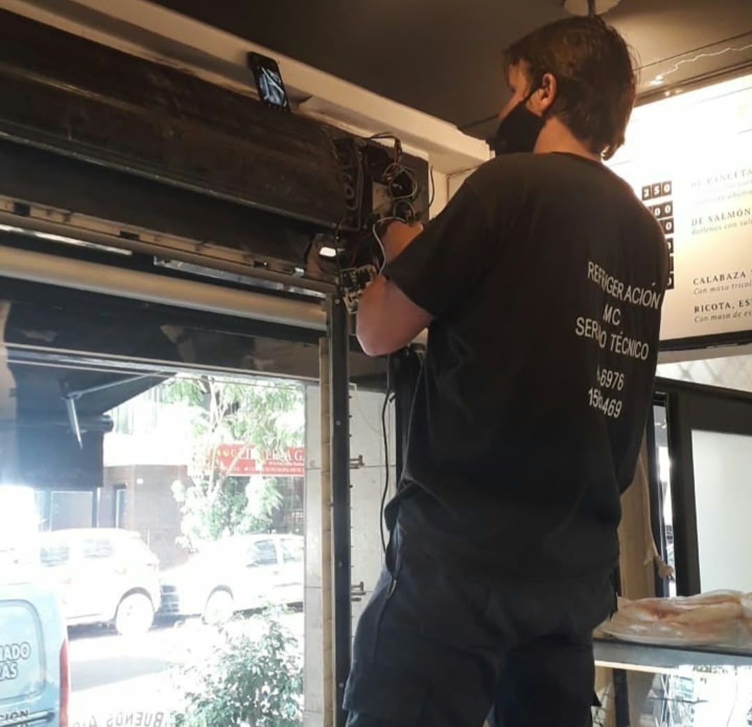 Técnico instalando un aire acondicionado de pared dentro del escaparate de una tienda
