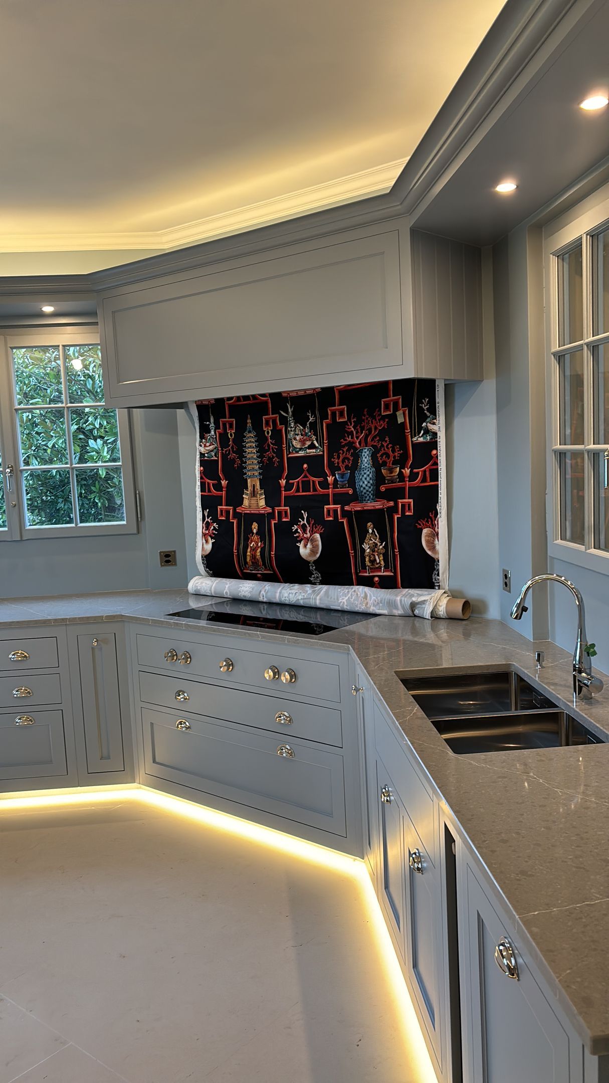 Cuisine blanche moderne avec placards incurvés, plans de travail éclairés et un grand panneau mural coloré.