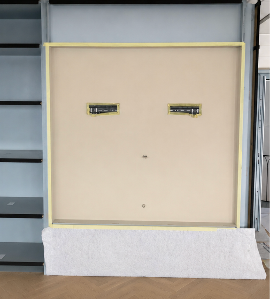 Armoire ou panneau beige avec bordures en ruban jaune et deux petites découpes rectangulaires dans un atelier.