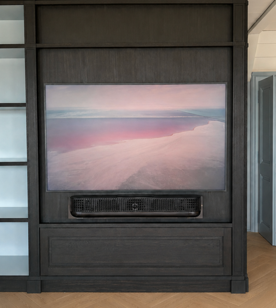 Photo de paysage encadrée au-dessus d'une grille d'aération noire dans un panneau mural en bois foncé, à l'intérieur d'une pièce moderne.