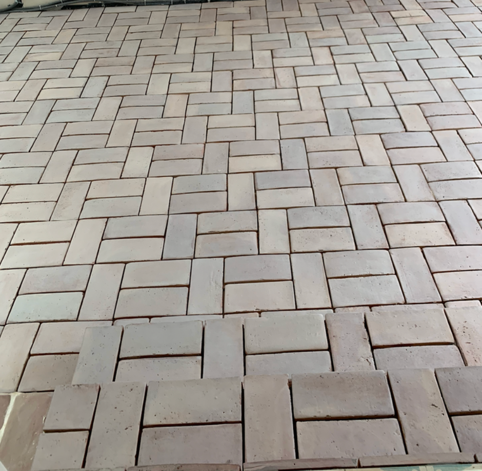 Pavés en pierre grise imbriqués, posés en chevrons à l'extérieur