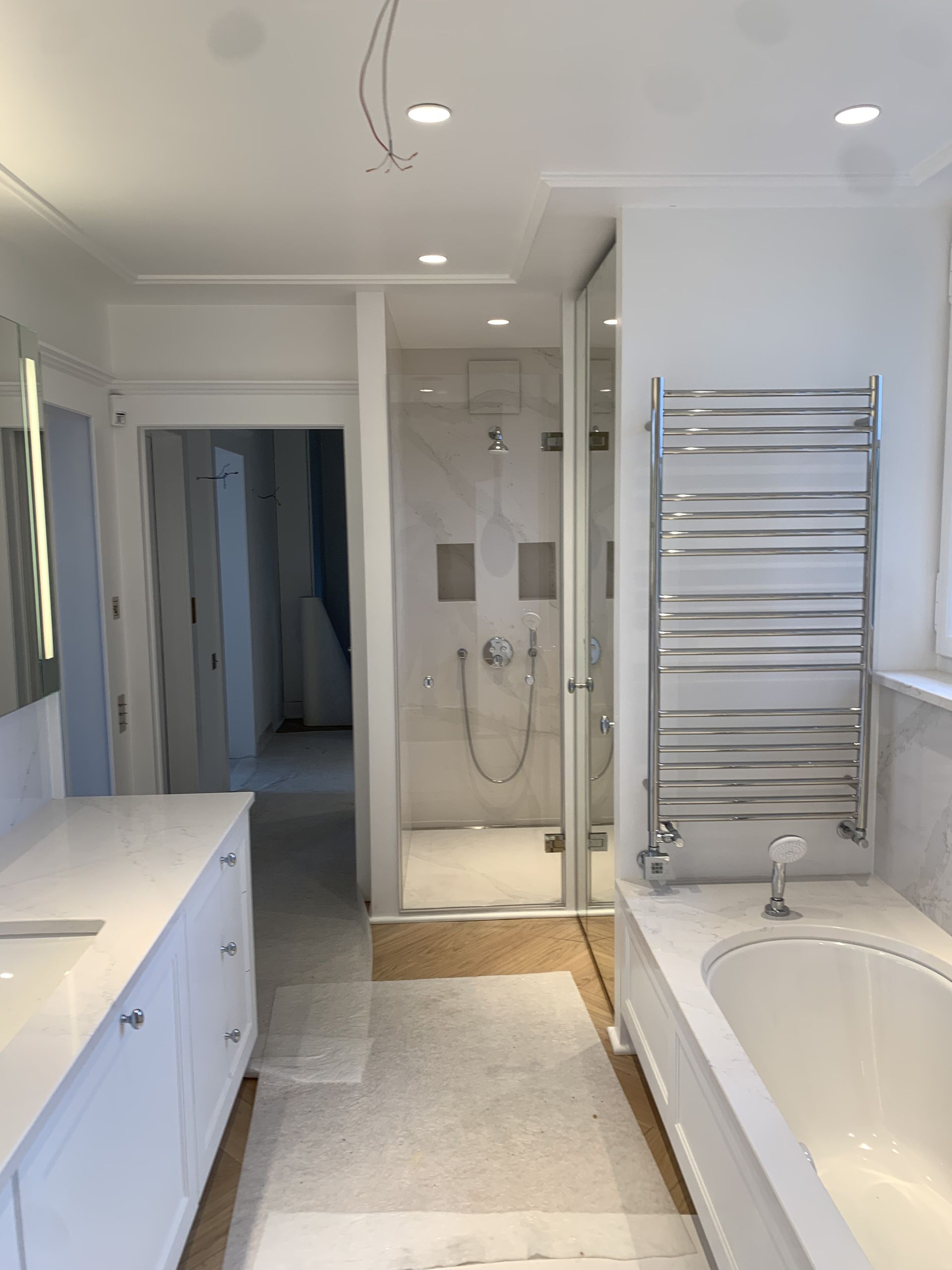 Salle de bain moderne et lumineuse avec baignoire, meuble-lavabo, douche à l'italienne et porte-serviettes