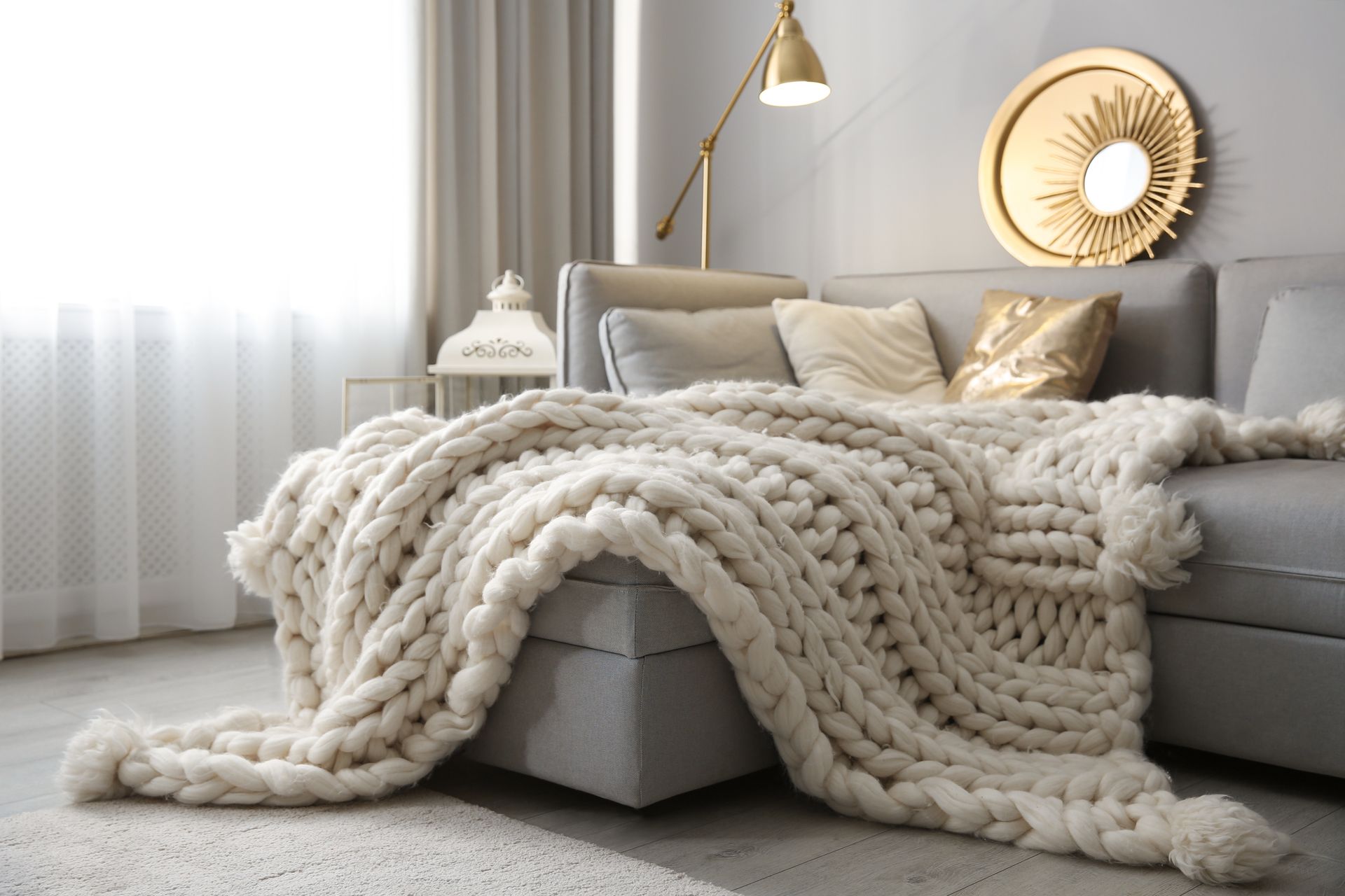 Cozy bedroom with a white bed, chunky knit throw, beige pillows, and soft natural light Cozy bedroom with a white bed, chunky knit throw, beige pillows, and soft natural light