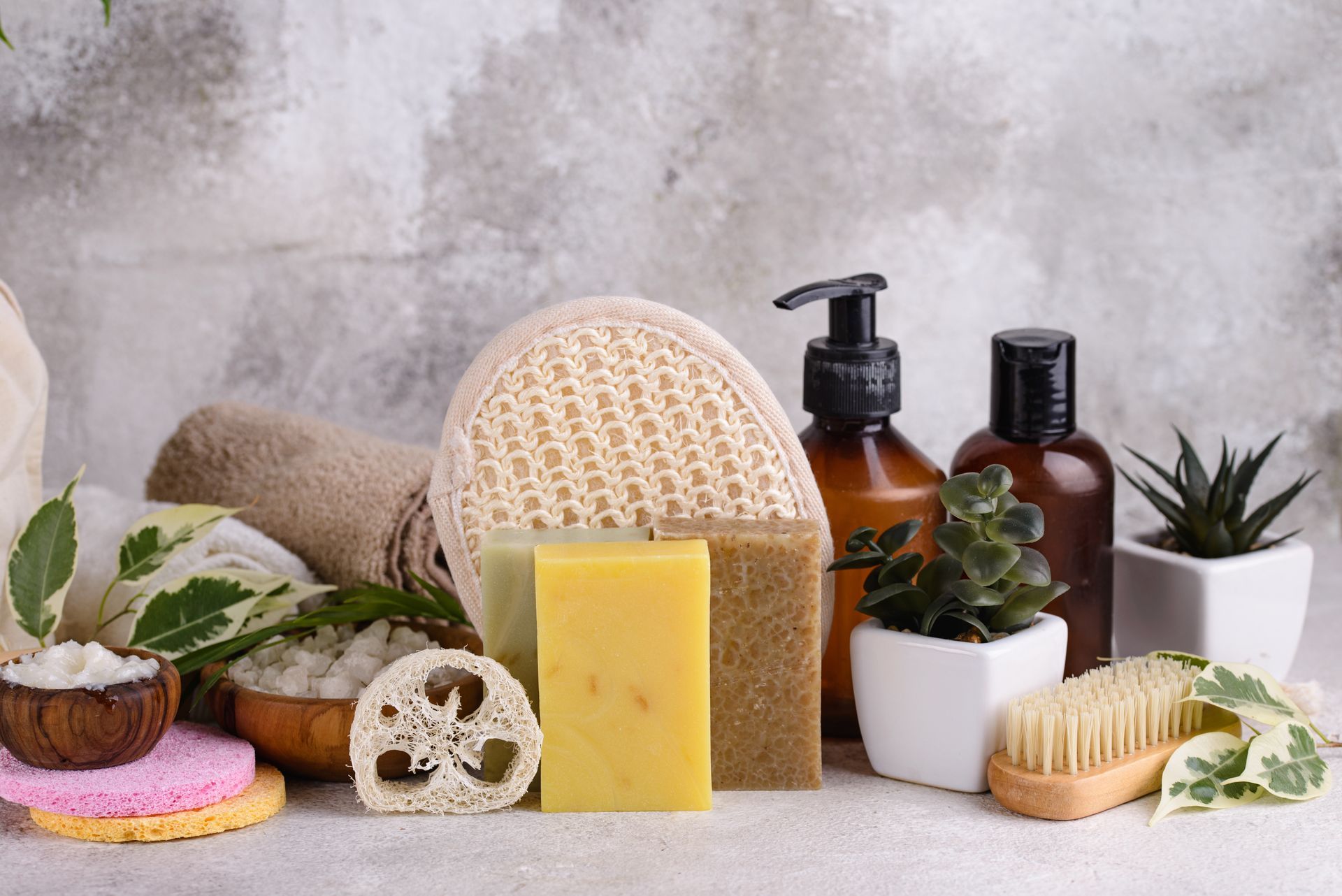 Spa products with soaps, brushes, candles, and potted plants on a stone surface Spa products with soaps, brushes, candles, and potted plants on a stone surface