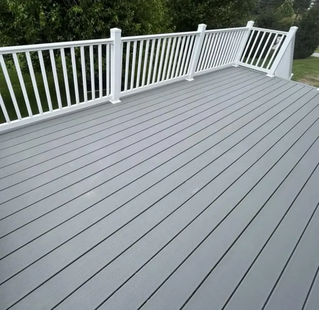 White-deck patio with gray flooring and white railings overlooking green trees