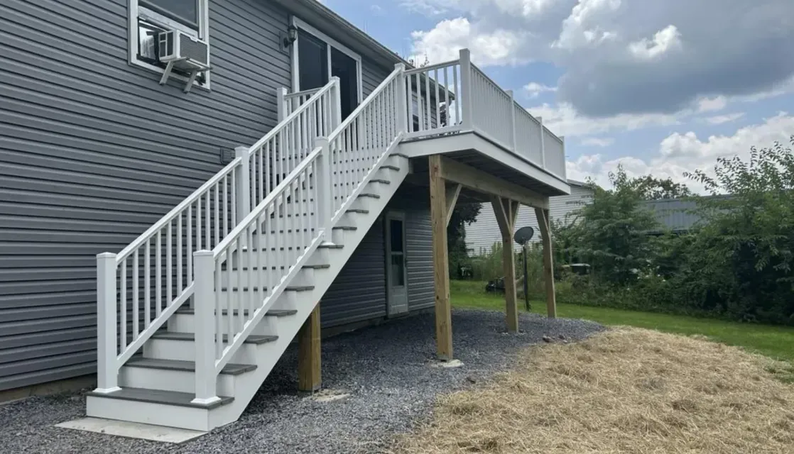 A beautiful gray home with a second-story deck addition and pristine white railings done by Dayhoff Construction.