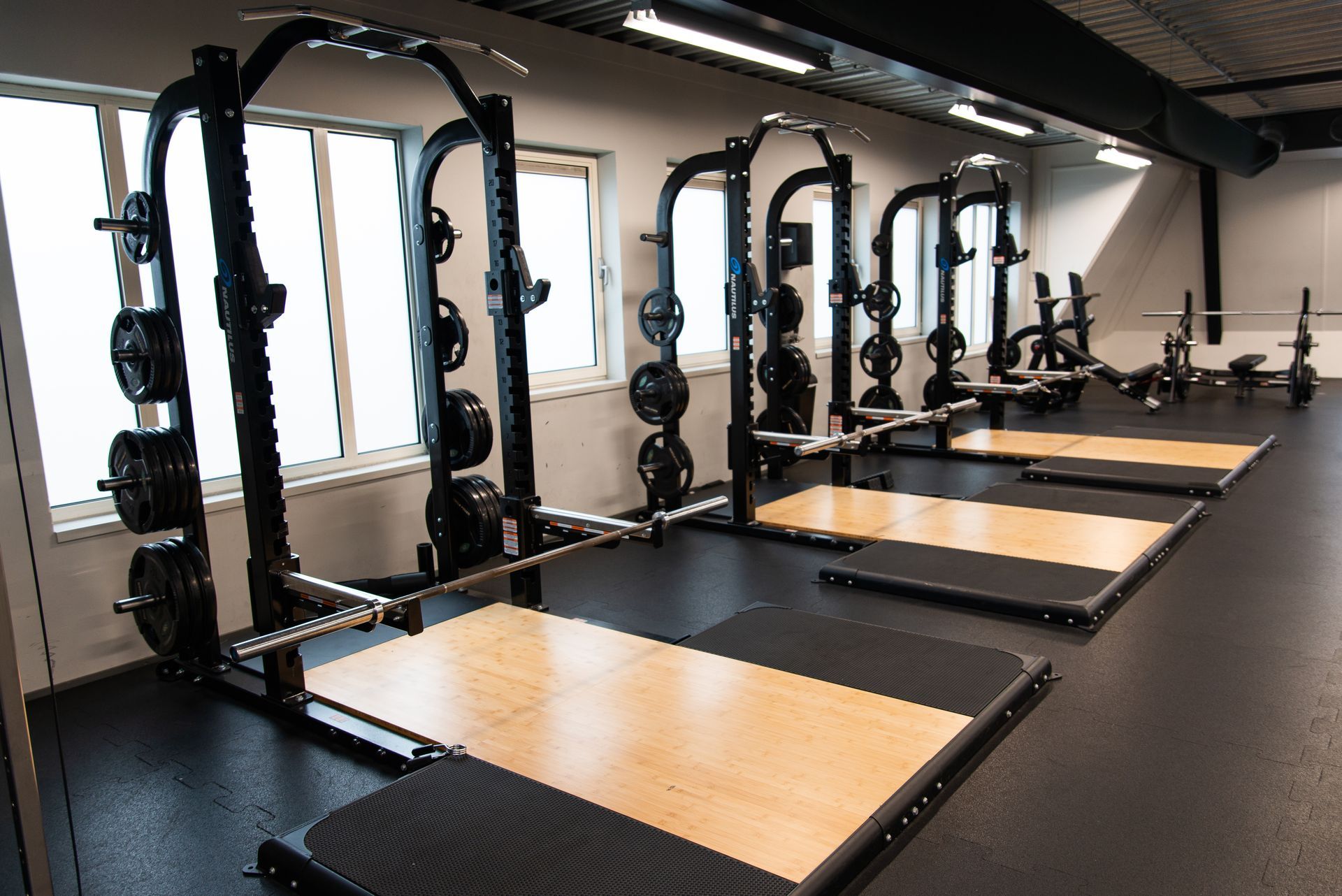 In een sportschool staat een rij squatrekken opgesteld.