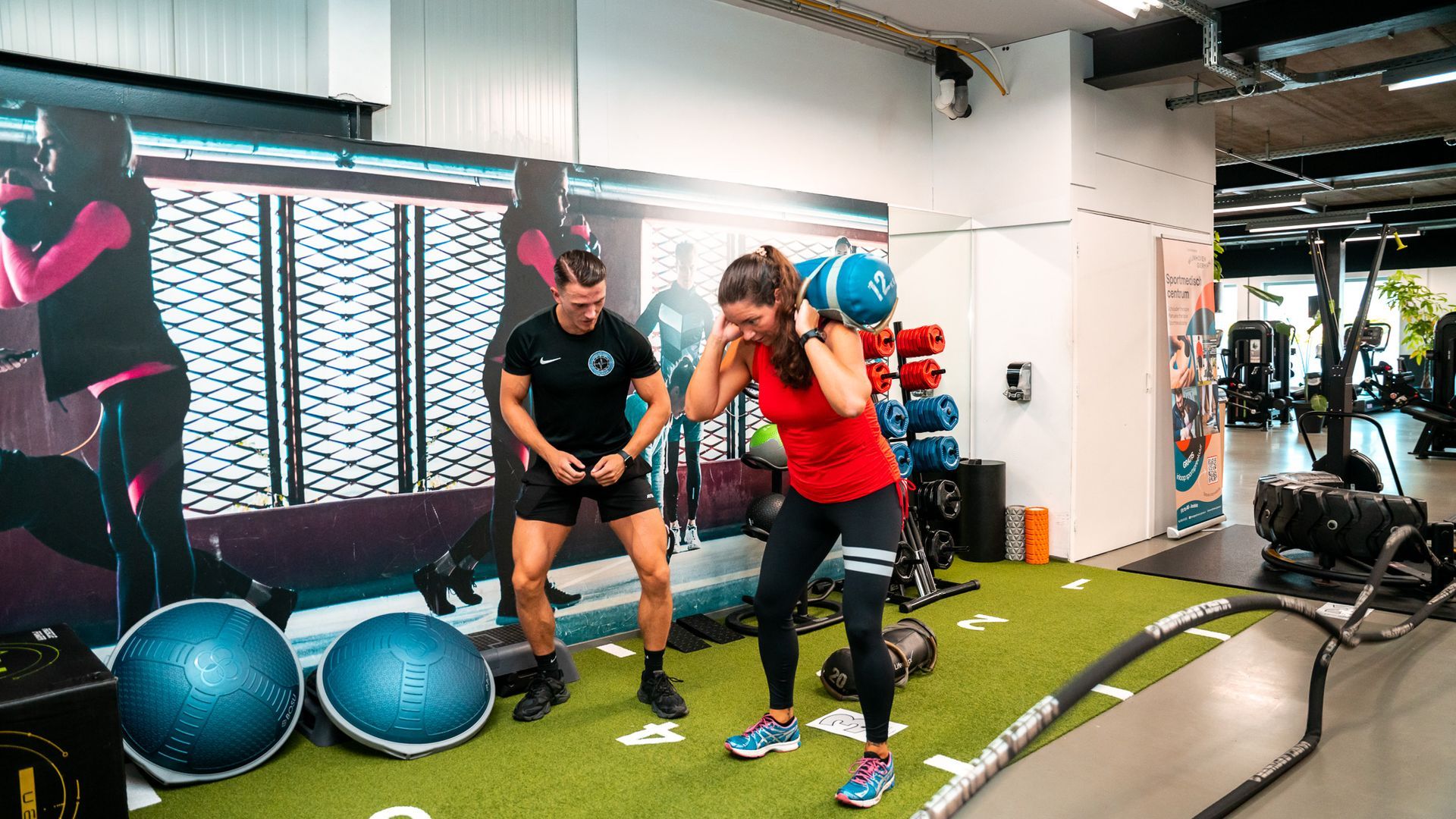 Een man houdt een touw vast in een sportschool terwijl een andere man toekijkt.