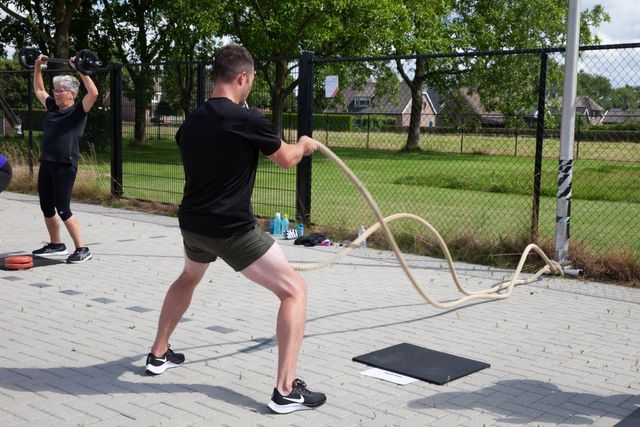 Een man houdt een touw vast in een park terwijl een andere man achter hem staat.