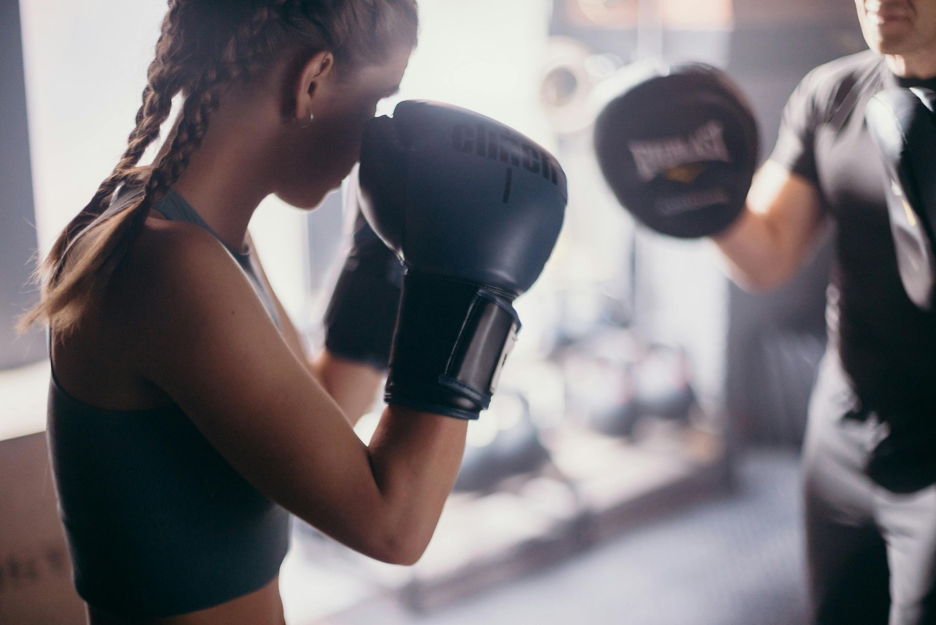 Een vrouw met bokshandschoenen die kickbox aan het oefenen is met een man.