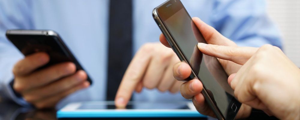 Two people are holding cell phones in their hands.