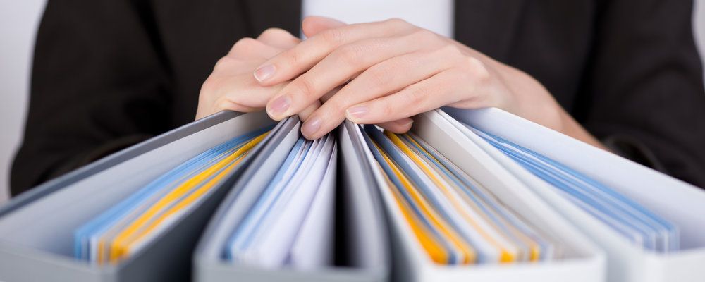 A woman is holding a stack of binders in her hands.