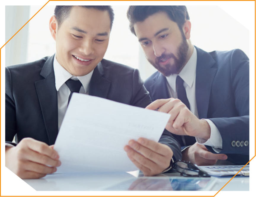 Two men in suits are looking at a piece of paper
