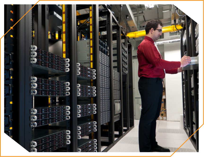 A man in a red shirt is working in a server room