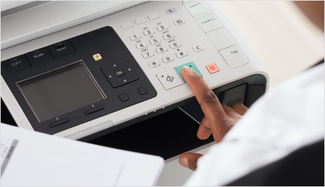 A person is pressing a button on a printer.