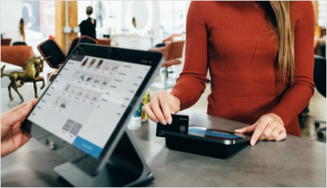 A woman is using a credit card to pay for something on a tablet.