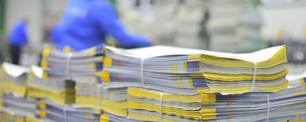 A stack of magazines is being printed in a factory.
