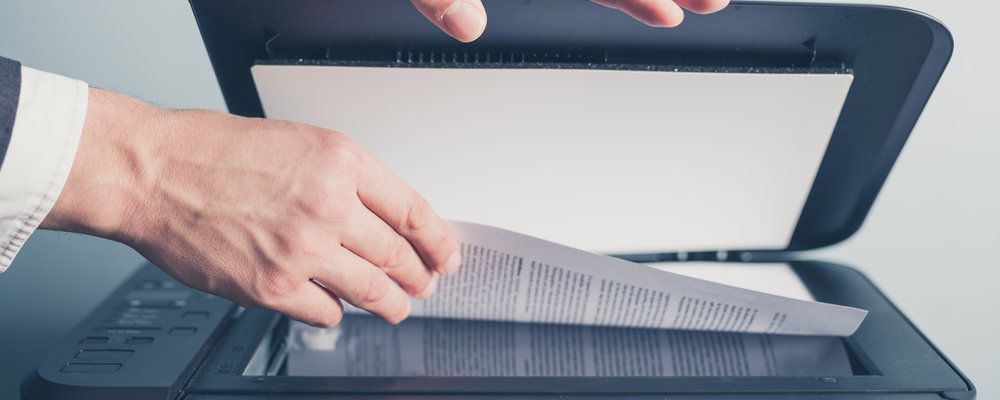 A person is scanning a piece of paper into a printer.