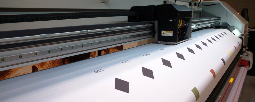 A large printer is printing a large piece of paper.