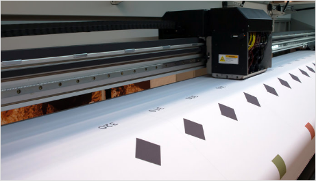 A large printer is printing a large piece of paper