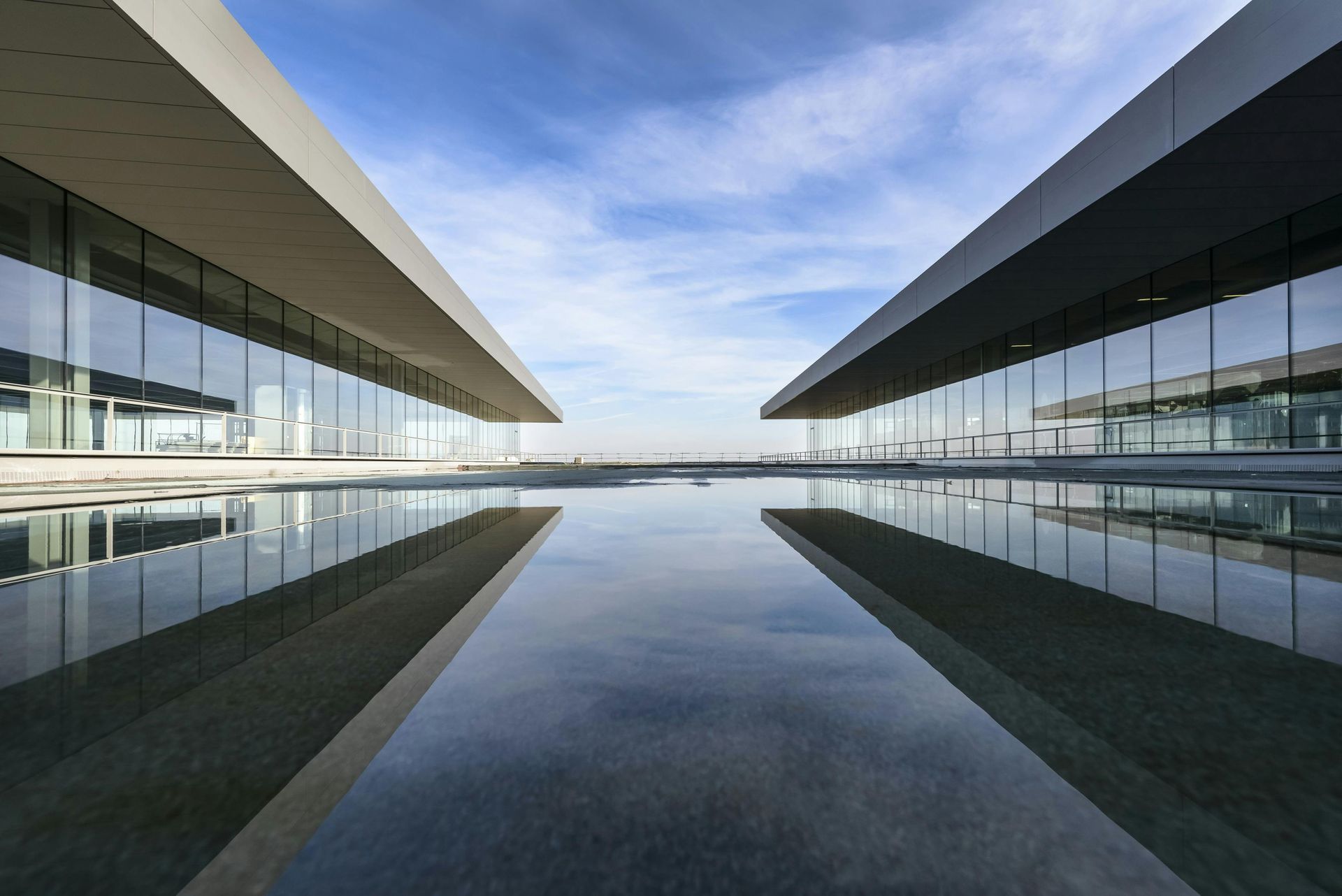 Modern building with mirrored facade reflecting the sky and surroundings.