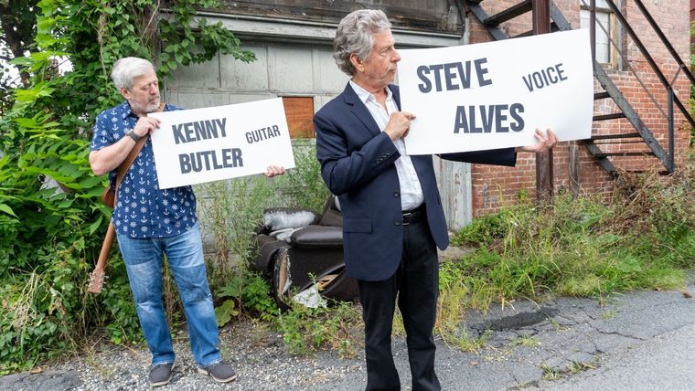 Kenny Butler and Steve Alves holding signs with their names and instruments