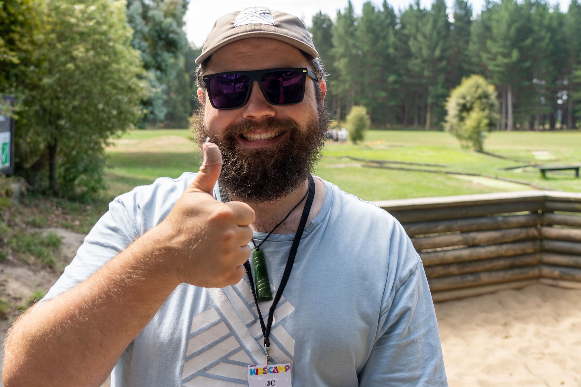A man with a beard and sunglasses is giving a thumbs up.