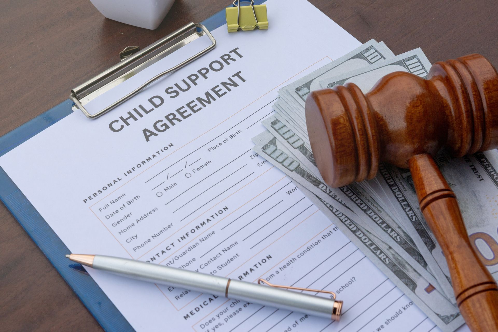 Child Support Agreement document with gavel, pen, and money on a desk.
