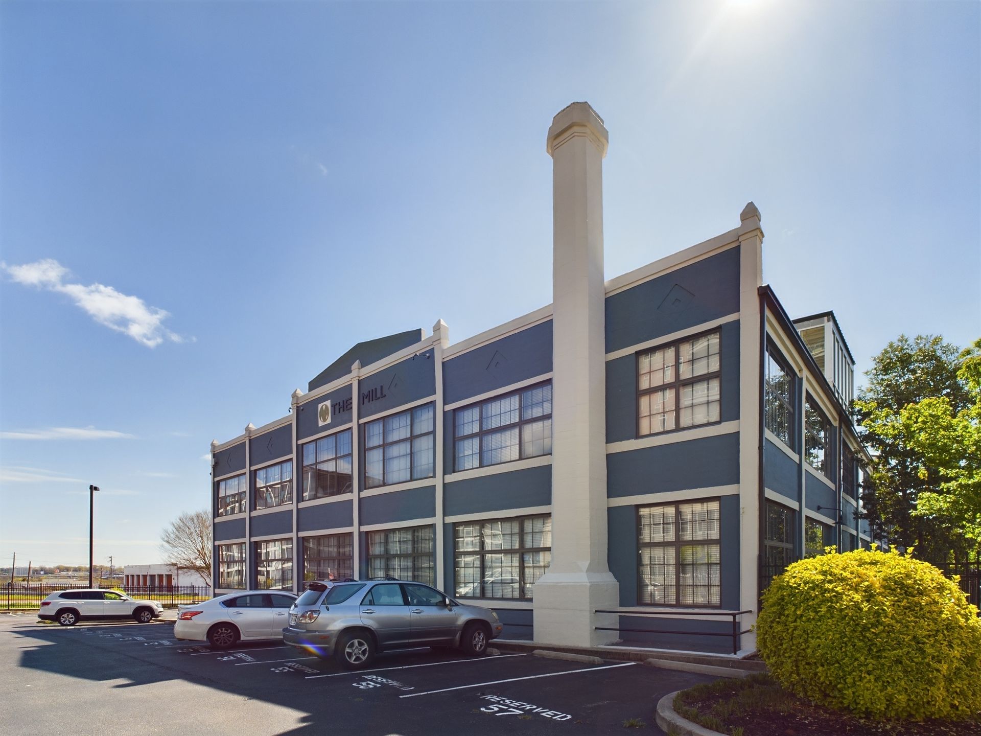 A large building with cars parked in front of it on a sunny day.