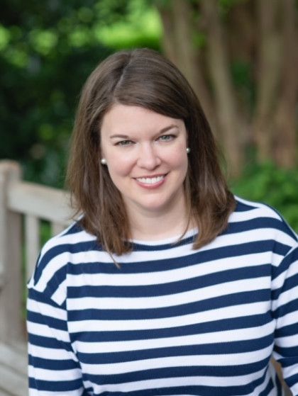 A woman wearing a blue and white striped shirt is smiling
