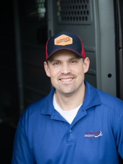 A man wearing a blue shirt and a hat is smiling for the camera