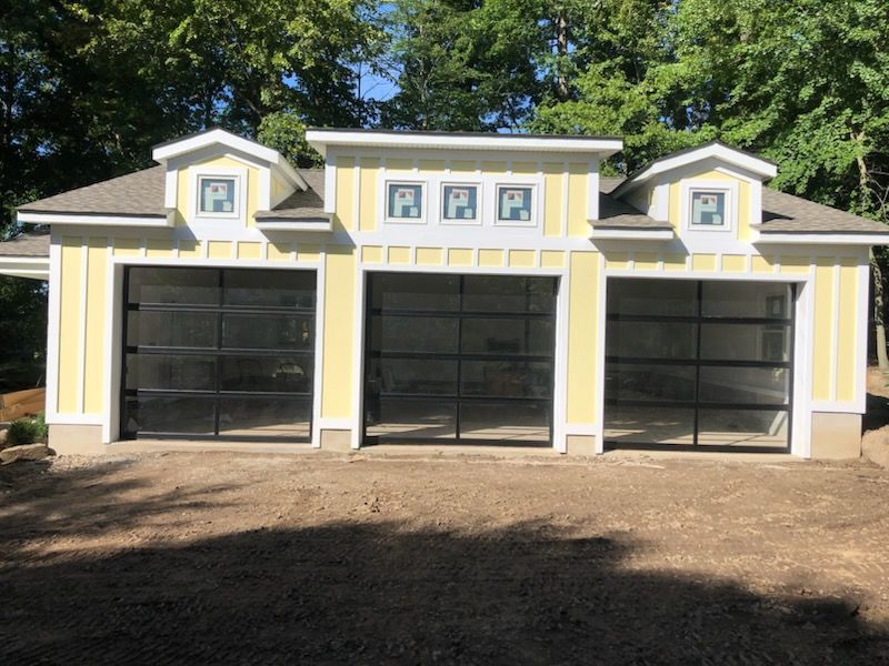 A yellow garage with clear glass doors and a white roof
