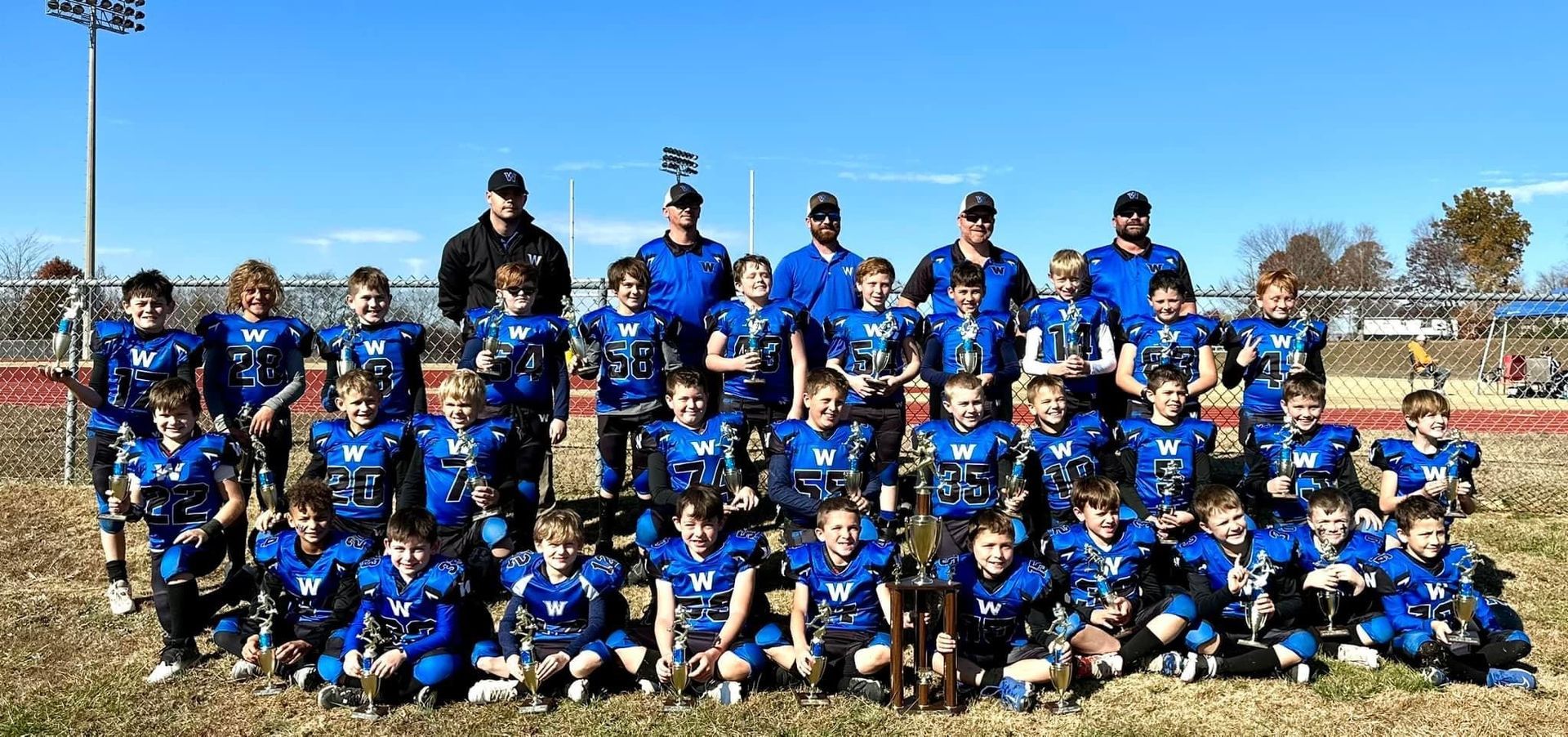 A group of young football players are posing for a picture on a field.