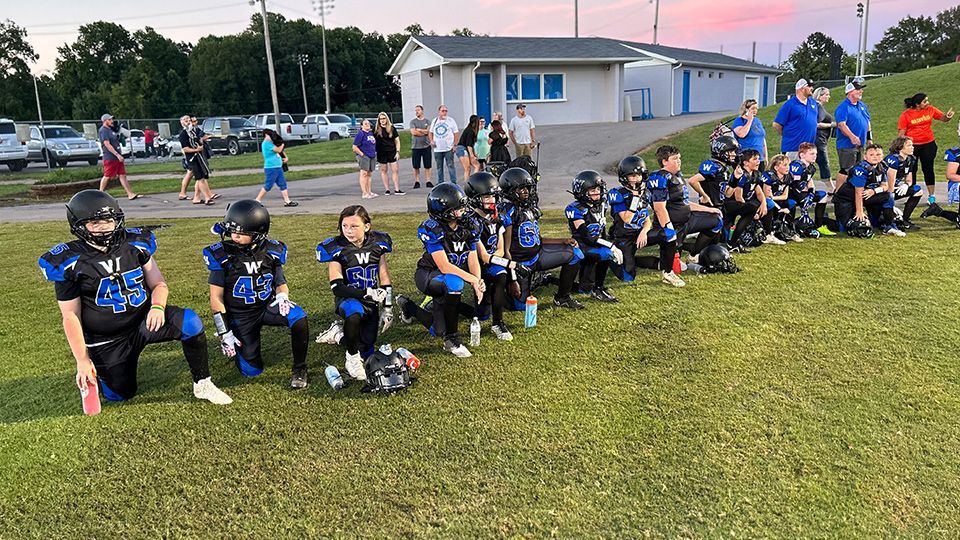 A group of young football players are sitting on the field.