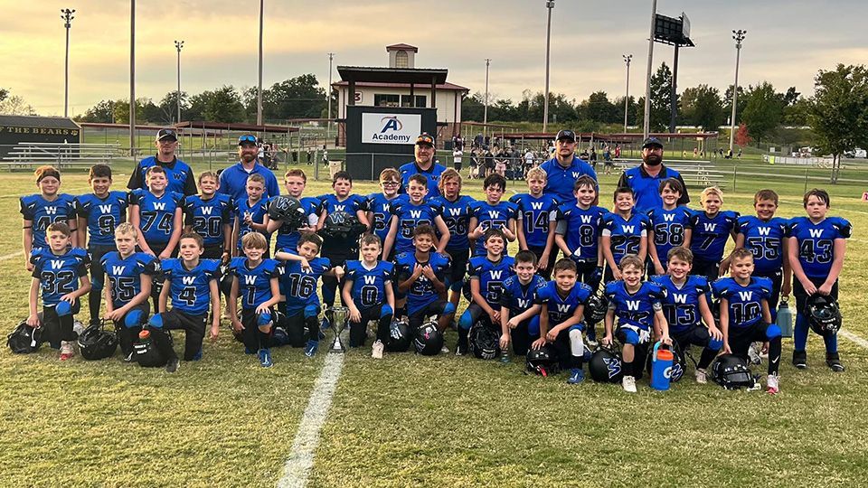 A group of young boys are posing for a picture on a football field.