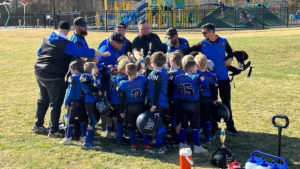 A group of young boys are huddled together on a football field.