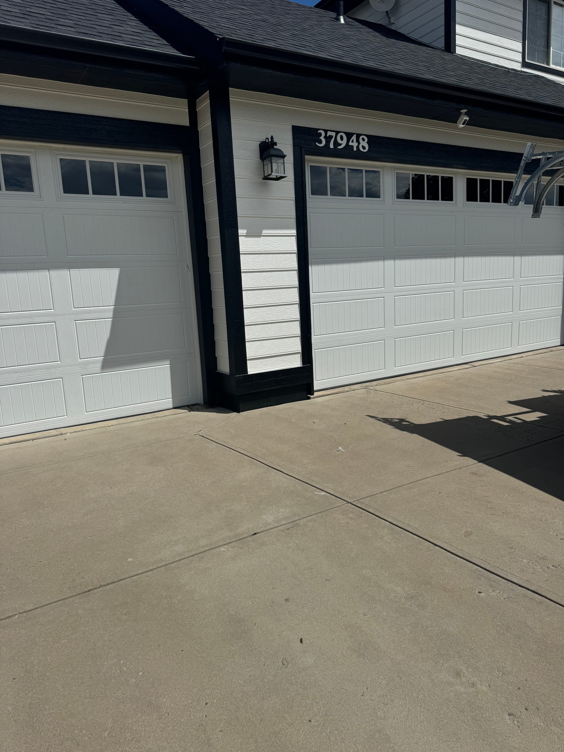 A man is kneeling down in a garage working on a garage door.