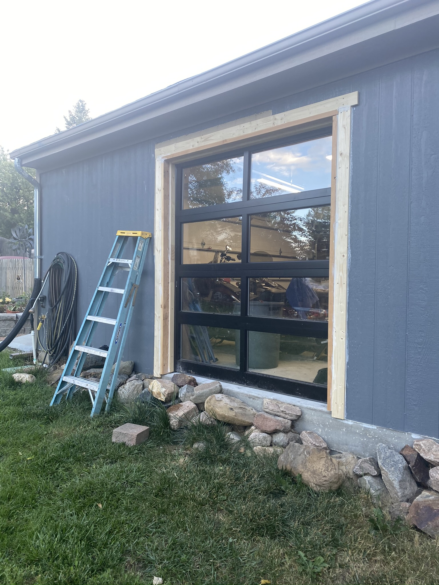 A ladder is sitting in front of a garage door that is being installed.